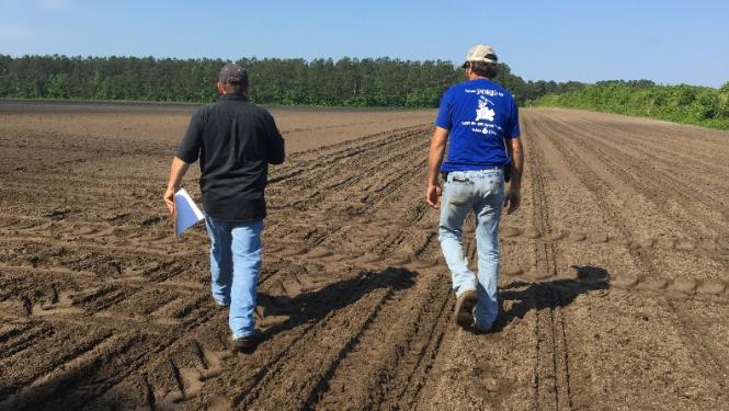 Two men walking through dirt field